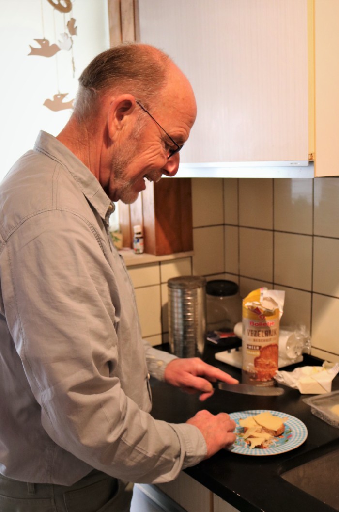Vrijwilliger Frans smeert een boterham bij mensen thuis